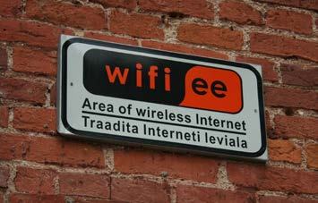A rectangular sign on a brick wall indicating "wifi ee" and "Area of wireless Internet" in English and Estonian.