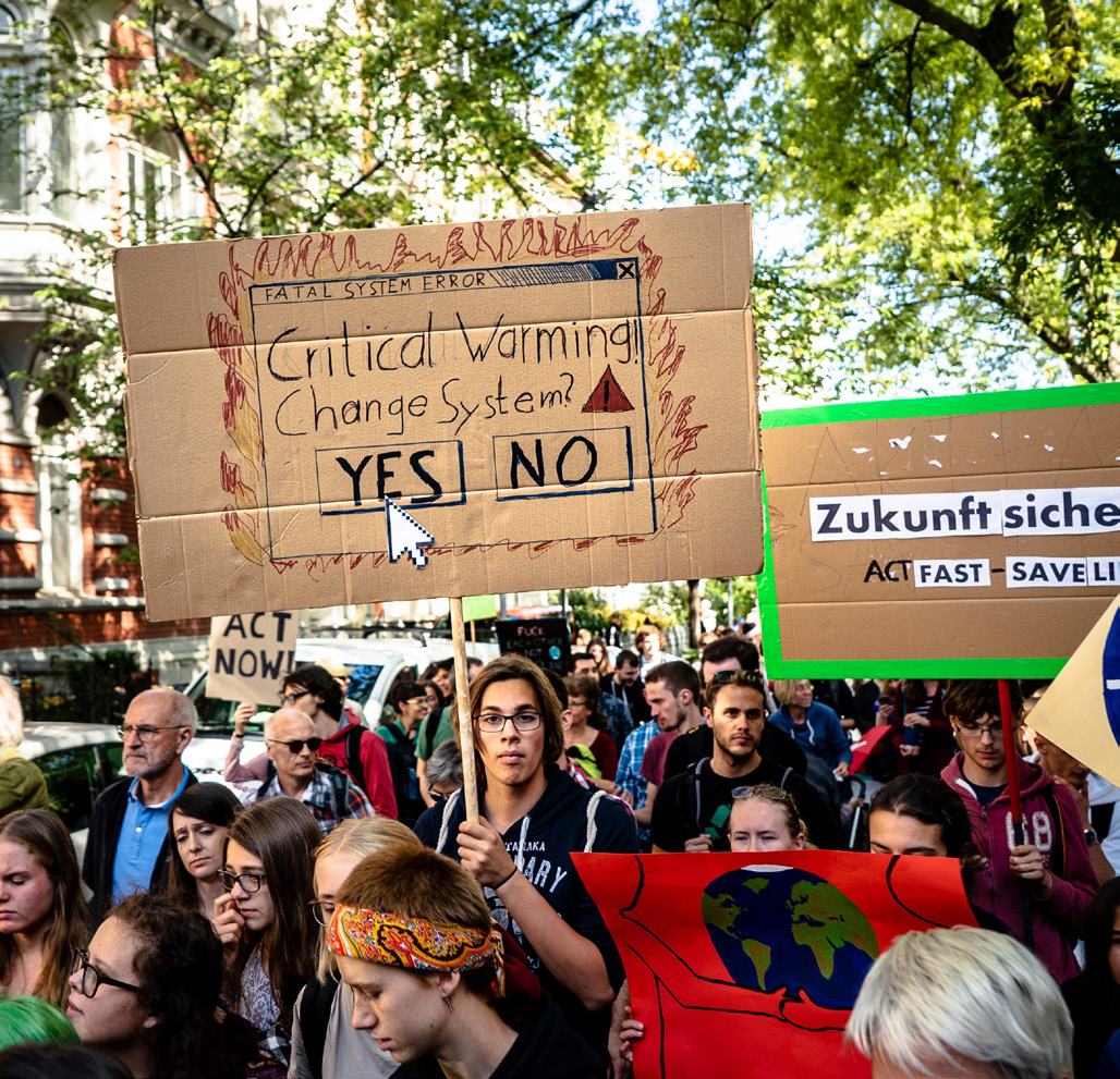 A protestor holding a sign designed like a computer error message that reads "FATAL SYSTEM ERROR Critical Warming Change System? YES NO" at a climate change demonstration.