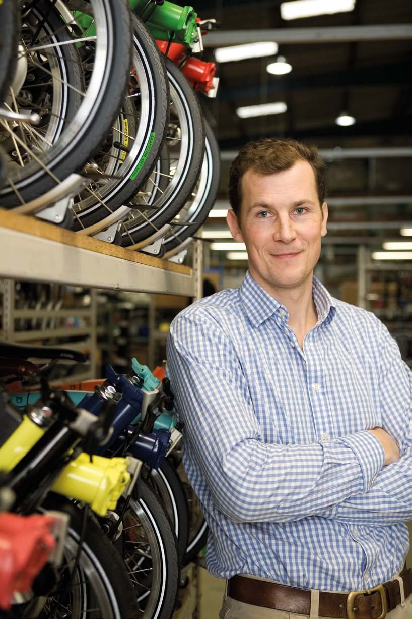 Man in a bicycle workshop standing next to shelves of bicycle wheels and frames.