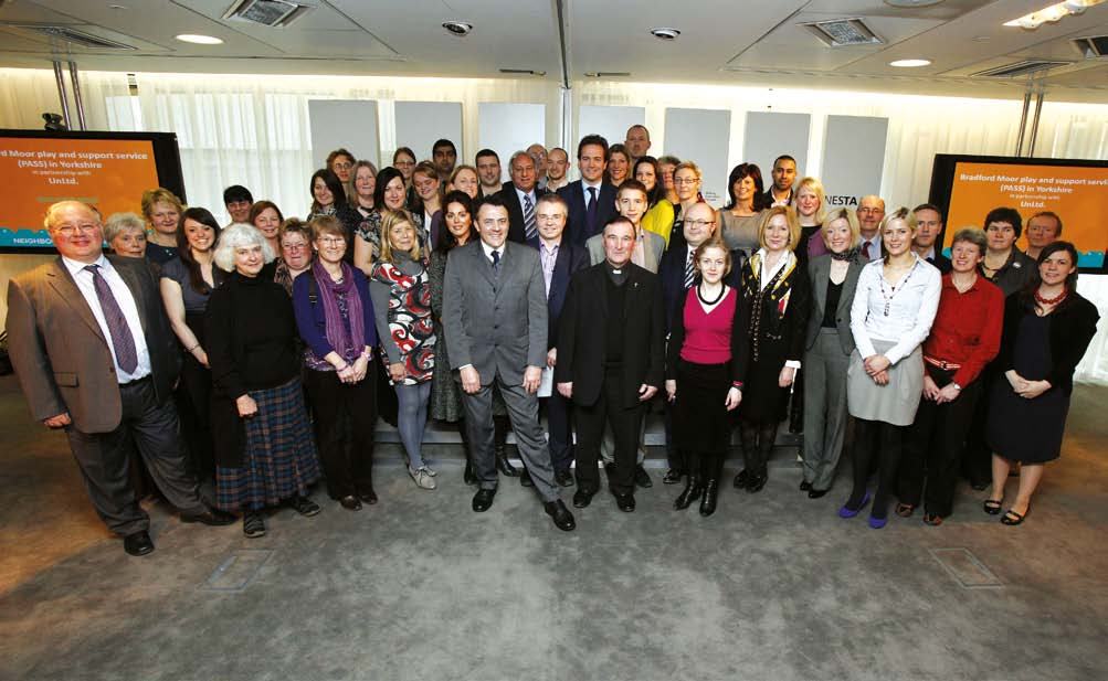 A large group of people posing for a photo, with screens in the background referencing "Bradford Moor play and support service (PASS)".