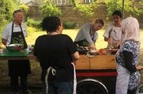 Diverse group of people preparing food at an outdoor stall, likely during a community event or food demonstration.