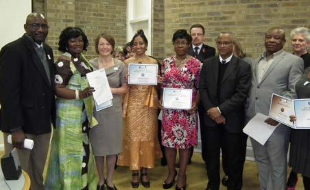 Group of diverse people, some holding certificates, at an awards ceremony or graduation event.